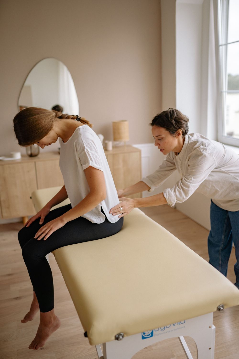 A therapist checking a seated patient's lower back posture
